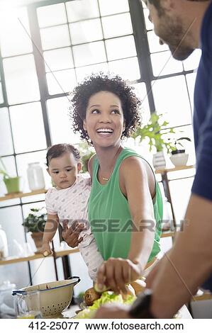 Stock Photo - Happy family preparing meal in domestic kitchen. Fotosearch