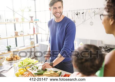 Stock Photo - Happy family preparing meal in domestic kitchen. Fotosearch