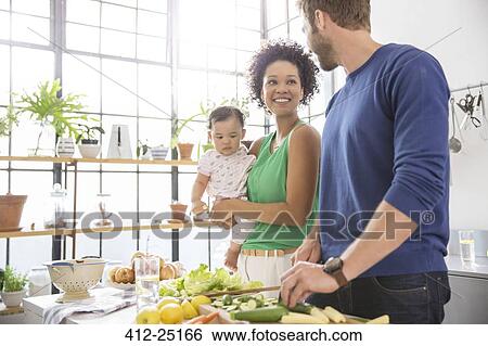 Stock Photograph - Happy family preparing meal in domestic kitchen. Fotosearch