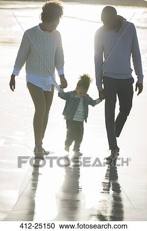 Stock Image - Happy family walking on beach. Fotosearch