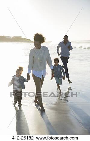 Stock Image - Happy walking on beach at sunset. Fotosearch