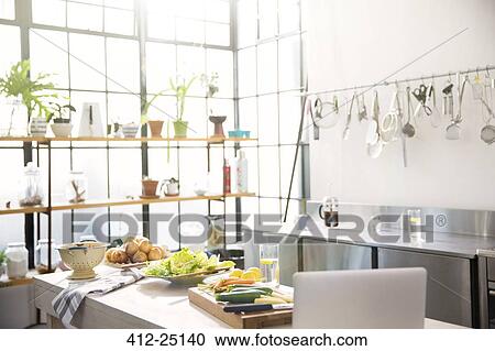 Stock Image - Interior of domestic kitchen with vegetables on kitchen counter. Fotosearch