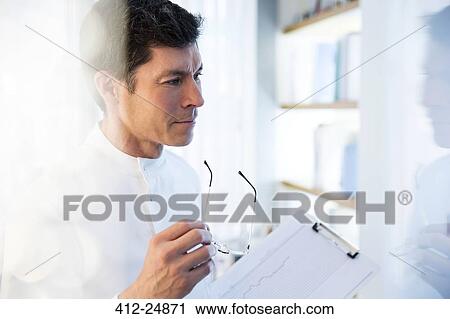 "looking away, View of man in laboratory holding glasses and chart" View Large Photo Image Stock Image - "looking away, View of man in laboratory holding glasses and chart". Fotosearch