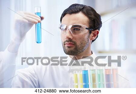 Man in laboratory looking at vial with blue fluid View Large Photo Image Stock Image - Man in laboratory looking at vial with blue fluid. Fotosearch