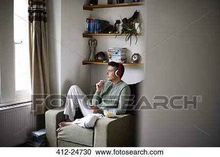 Man sitting in armchair with headphones looking through window View Large Photo Image Stock Image - Man sitting in armchair with headphones looking through window. Fotosearch