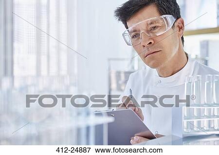 Stock Photo - Man working in laboratory holding chart. Fotosearch