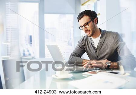 Stock Image - Man working using laptop in office. Fotosearch