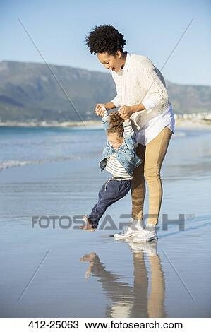 Stock Image - Mother and daughter playing on beach. Fotosearch