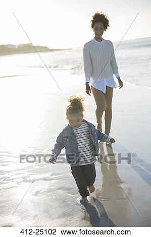 Stock Image - Mother and daughter walking on beach. Fotosearch