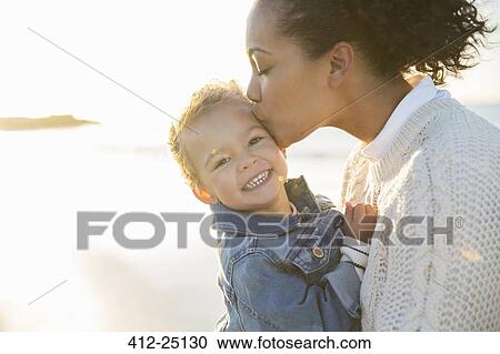 Mother kissing daughter on beach View Large Photo Image Stock Image - Mother kissing daughter on beach. Fotosearch