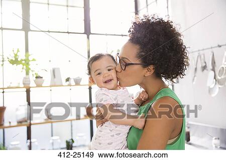 Mother kissing her daughter in domestic kitchen View Large Photo Image Stock Photo - Mother kissing her daughter in domestic kitchen. Fotosearch