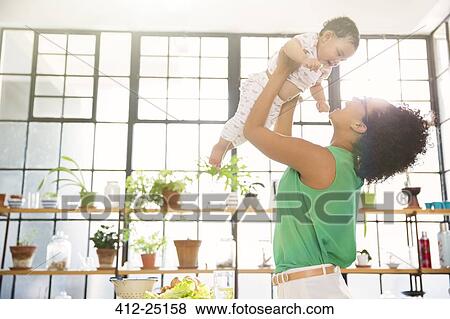 Mother lifting her daughter overhead View Large Photo Image Stock Photo - Mother lifting her daughter overhead. Fotosearch