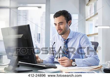 Portrait of man sitting at his desk in office View Large Photo Image Stock Photograph - Portrait of man sitting at his desk in office. Fotosearch