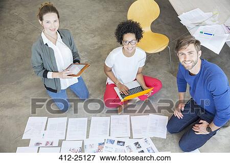 Portrait of three young people sitting on floor and working together in studio View Large Photo Image Stock Photo - Portrait of three young people sitting on floor and working together in studio. Fotosearch
