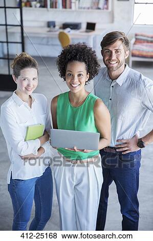 Stock Photo - Portrait of three young people standing with digital tablet in studio. Fotosearch