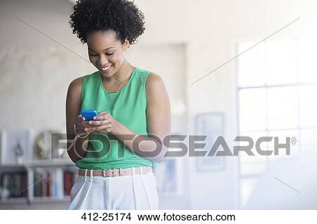 Portrait of woman with black curly hair holding mobile phone View Large Photo Image Picture - Portrait of woman with black curly hair holding mobile phone. Fotosearch