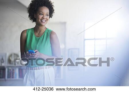 Stock Photograph - Portrait of woman with black curly hair holding mobile phone. Fotosearch