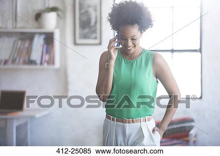 Stock Photography - Portrait of woman with black curly hair talking on mobile phone. Fotosearch