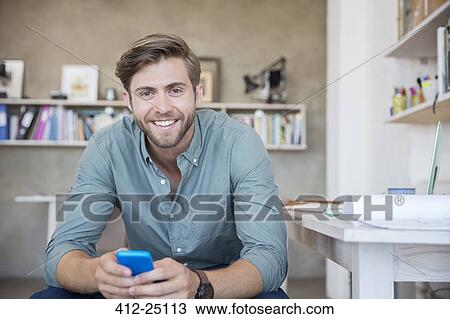 Portrait of young blonde man sitting with mobile phone View Large Photo Image Stock Image - Portrait of young blonde man sitting with mobile phone. Fotosearch