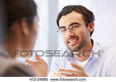 Smiling man in glasses in office with client View Large Photo Image Stock Photography - Smiling man in glasses in office with client. Fotosearch