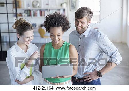 Three young people looking at digital tablet in studio View Large Photo Image Picture - Three young people looking at digital tablet in studio. Fotosearch