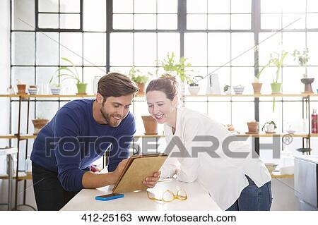 Two young people looking at documents in domestic kitchen View Large Photo Image Stock Image - Two young people looking at documents in domestic kitchen. Fotosearch