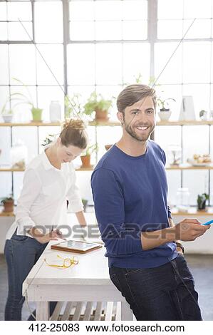 Two young people using different portable devices in domestic kitchen View Large Photo Image Stock Image - Two young people using different portable devices in domestic kitchen. Fotosearch
