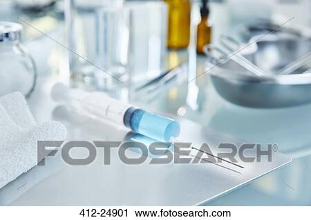 Stock Image - View of syringe with blue fluid on glass table in laboratory. Fotosearch
