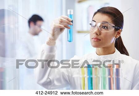 Woman in laboratory looking at vial with blue fluid View Large Photo Image Stock Image - Woman in laboratory looking at vial with blue fluid. Fotosearch