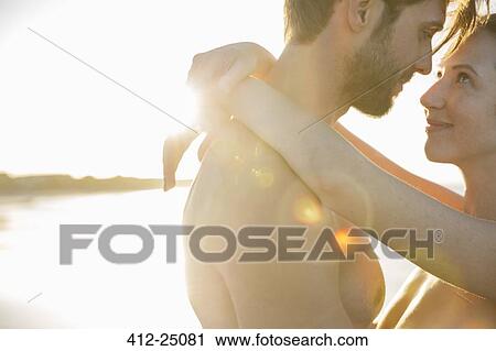 Stock Image - Young couple embracing on beach. Fotosearch