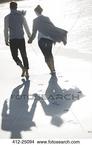 Young couple holding hands and walking on beach View Large Photo Image Picture - Young couple holding hands and walking on beach. Fotosearch