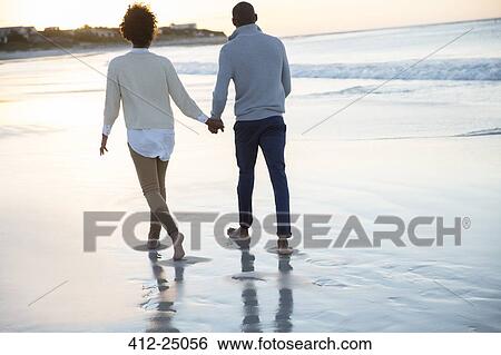 Young couple holding hands and walking on beach View Large Photo Image Stock Photograph - Young couple holding hands and walking on beach. Fotosearch