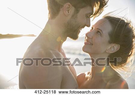 Stock Photo - Young couple looking at each other on beach. Fotosearch