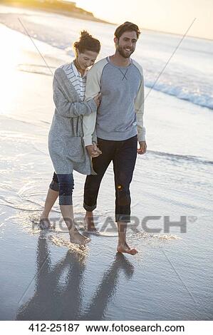 Young couple walking on beach in evening sun View Large Photo Image Stock Photo - Young couple walking on beach in evening sun. Fotosearch