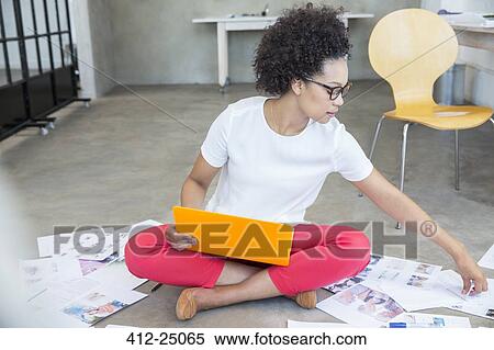 Stock Photography - Young woman sitting on floor and working with laptop. Fotosearch