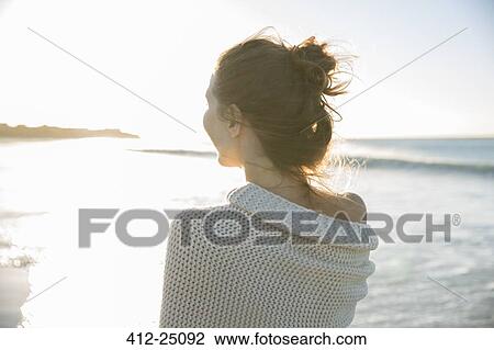 Young woman wrapped in blanket on beach View Large Photo Image Stock Image - Young woman wrapped in blanket on beach. Fotosearch