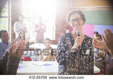 Picture - Audience clapping for woman in community center. Fotosearch