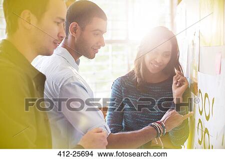 Picture - Business people examining proofs on board. Fotosearch