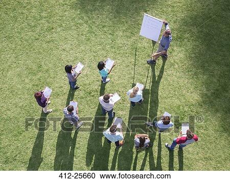 Businessman leading meeting at flipchart in sunny field View Large Photo Image Stock Image - Businessman leading meeting at flipchart in sunny field. Fotosearch