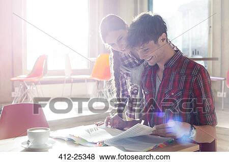 Casual business people reviewing document edits in sunny office View Large Photo Image Stock Photo - Casual business people reviewing document edits in sunny office. Fotosearch
