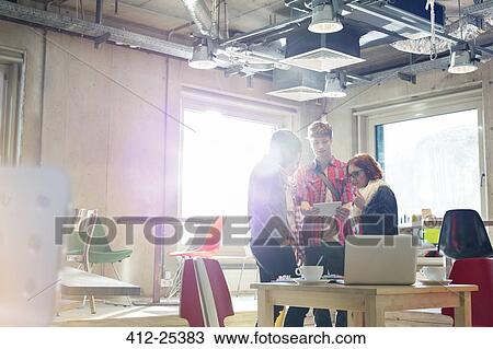 Stock Image - Casual business people using digital tablet in sunny office. Fotosearch