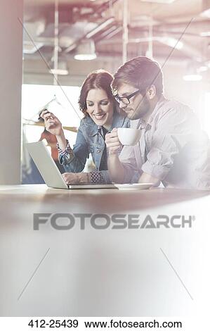 Casual business people working at laptop in office View Large Photo Image Stock Photo - Casual business people working at laptop in office. Fotosearch