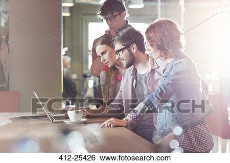 Casual business people working at laptop in sunny office View Large Photo Image Stock Photograph - Casual business people working at laptop in sunny office. Fotosearch