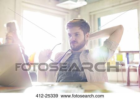 Casual businessman working at laptop in sunny office View Large Photo Image Stock Photo - Casual businessman working at laptop in sunny office. Fotosearch