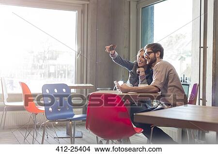 Picture - Couple taking selfie with camera phone in cafe. Fotosearch