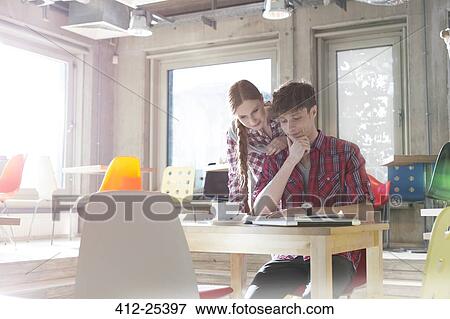 Creative business people reading in sunny office View Large Photo Image Stock Photo - Creative business people reading in sunny office. Fotosearch