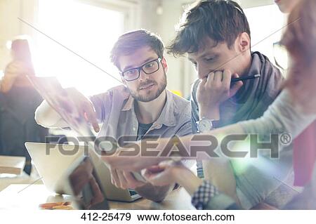 Creative business people reviewing proofs in sunny office View Large Photo Image Stock Photo - Creative business people reviewing proofs in sunny office. Fotosearch