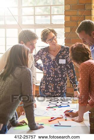 Creative business people reviewing proofs at table View Large Photo Image Stock Photo - Creative business people reviewing proofs at table. Fotosearch