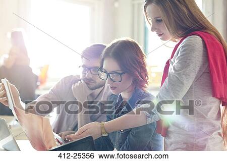 Creative business people reviewing document in sunny office View Large Photo Image Stock Photograph - Creative business people reviewing document in sunny office. Fotosearch