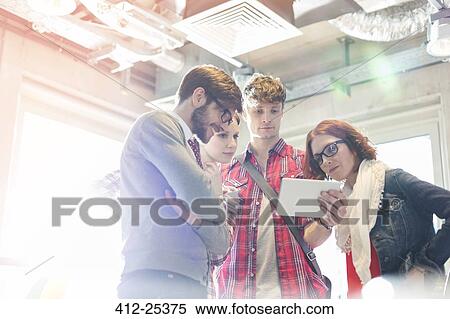 Creative business people sharing digital tablet in sunny office View Large Photo Image Stock Photography - Creative business people sharing digital tablet in sunny office. Fotosearch